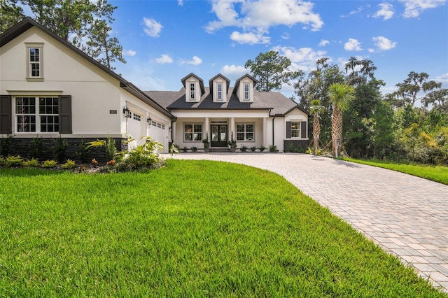 view of front of house with decorative driveway, stucco siding, an attached garage, a front yard, and stone siding