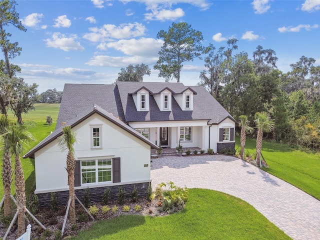 view of front of house with a shingled roof, stone siding, a front lawn, a porch, and stucco siding