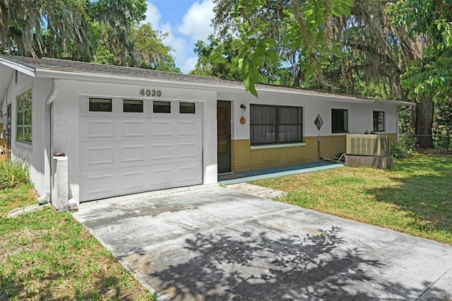 single story home featuring a garage, a front lawn, and central air condition unit