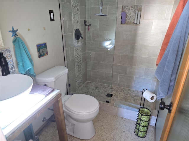 bathroom with tiled shower, sink, and toilet