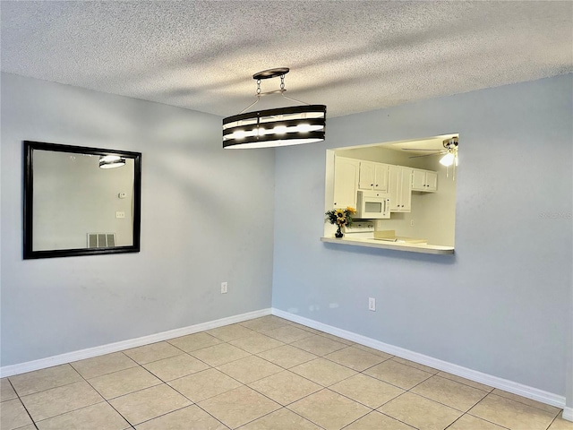 tiled spare room featuring ceiling fan and a textured ceiling