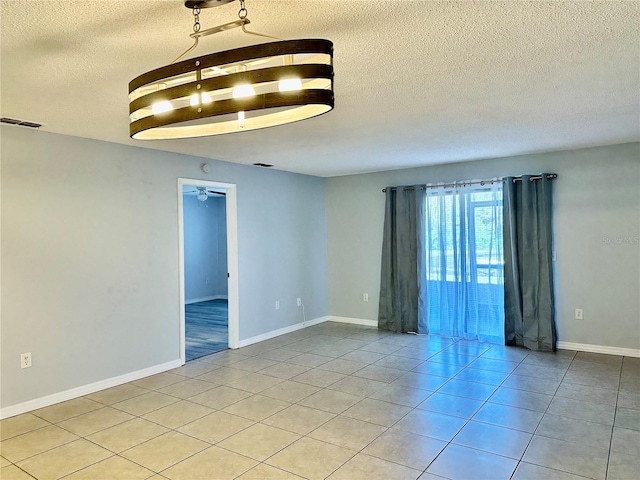 empty room with ceiling fan, a textured ceiling, and light tile patterned flooring