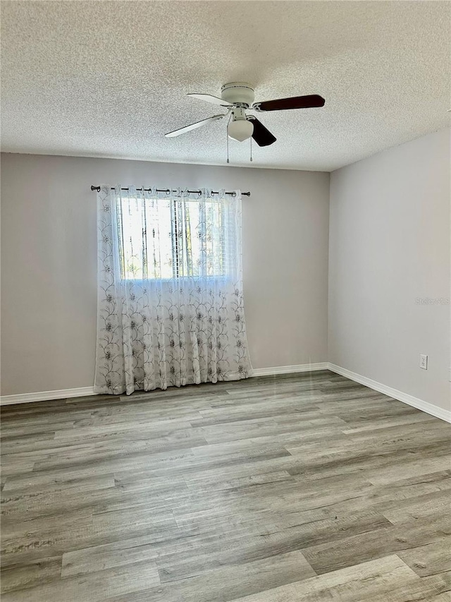 spare room featuring ceiling fan, light hardwood / wood-style floors, and a textured ceiling