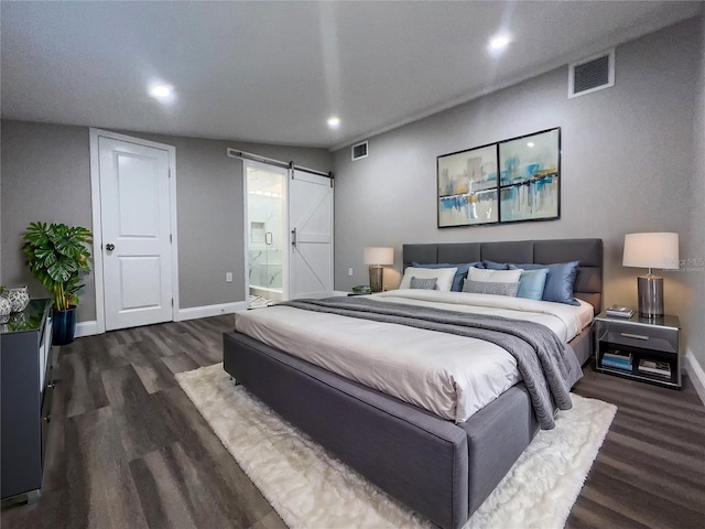 bedroom featuring dark hardwood / wood-style floors, a barn door, and ensuite bathroom