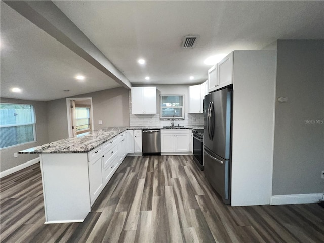 kitchen featuring stainless steel appliances, light stone countertops, white cabinets, and kitchen peninsula