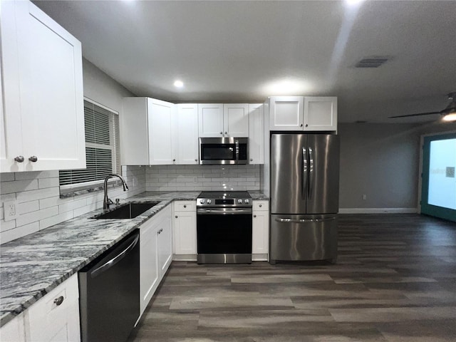 kitchen with sink, white cabinetry, stainless steel appliances, light stone counters, and dark hardwood / wood-style flooring