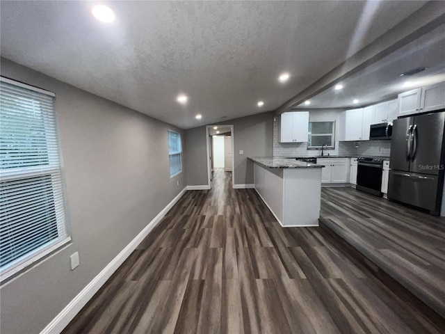 kitchen with stone counters, white cabinetry, stainless steel appliances, dark hardwood / wood-style floors, and kitchen peninsula