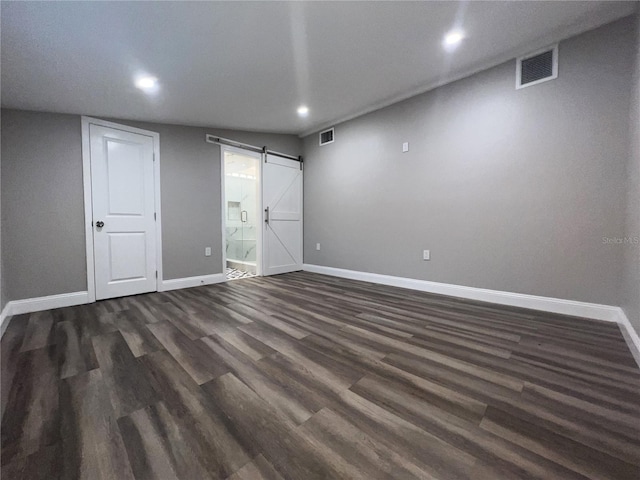 empty room with dark hardwood / wood-style floors and a barn door