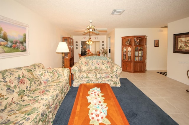 living room with a textured ceiling, ceiling fan, and light tile patterned floors