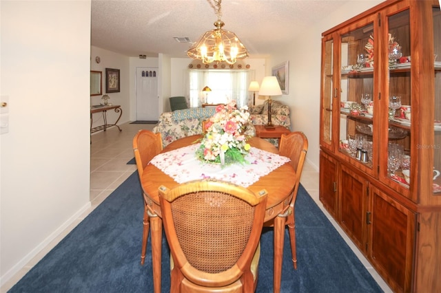 tiled dining area featuring a chandelier and a textured ceiling