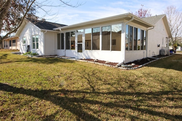 rear view of house featuring a sunroom and a lawn