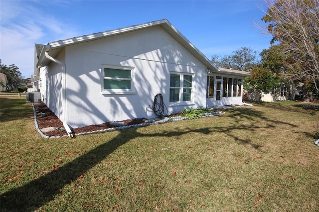 rear view of property featuring a lawn and cooling unit