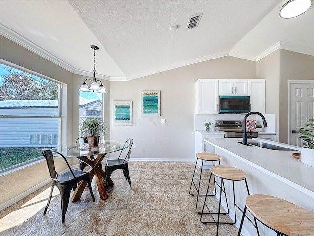 dining space with a textured ceiling, lofted ceiling, sink, and ornamental molding