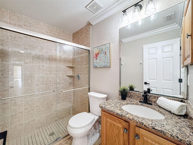 bathroom with a shower with shower door, vanity, a textured ceiling, crown molding, and toilet