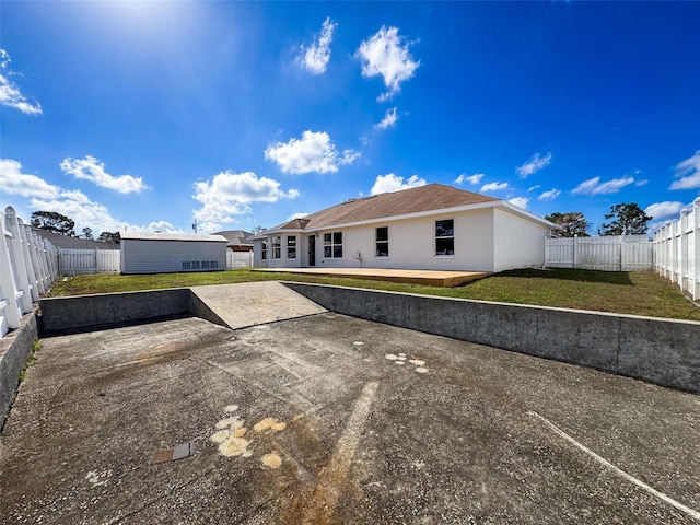 back of property with a storage unit, a patio, and a lawn