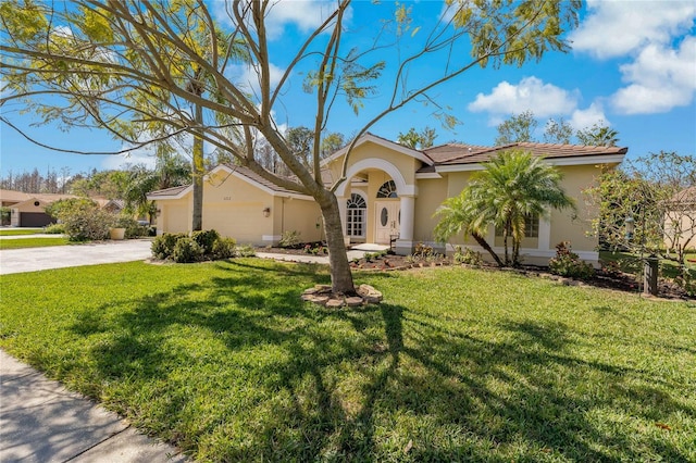 mediterranean / spanish home with a garage, concrete driveway, a front yard, and stucco siding