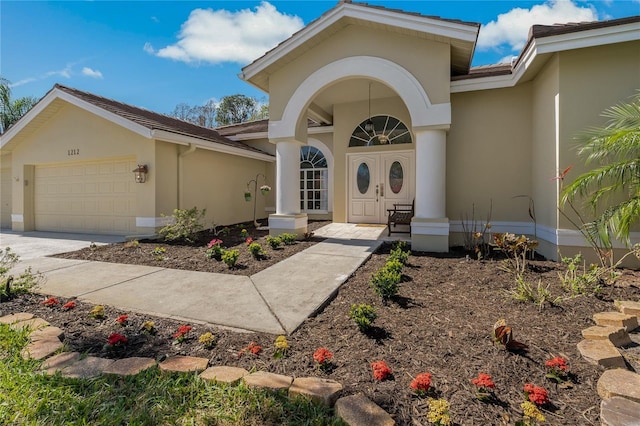 view of exterior entry with an attached garage, concrete driveway, and stucco siding