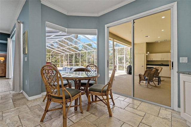 dining area with a sunroom, stone tile floors, ornamental molding, and baseboards