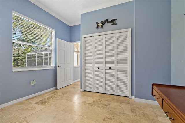 bedroom with a textured ceiling, ornamental molding, a closet, and baseboards