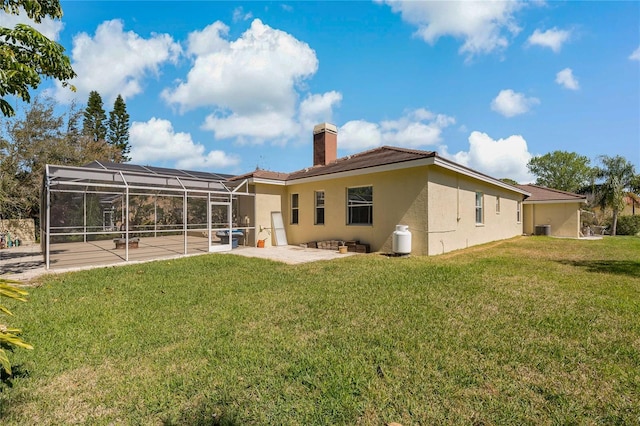 back of house featuring a lanai, a yard, stucco siding, a chimney, and a patio area