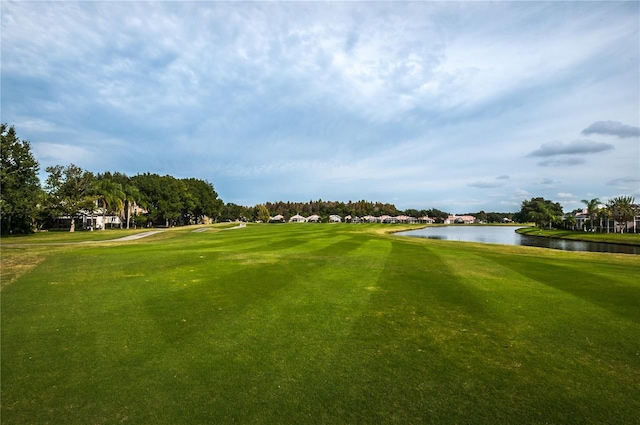 view of community featuring view of golf course, a water view, and a yard