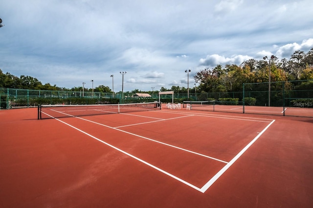 view of tennis court featuring community basketball court and fence