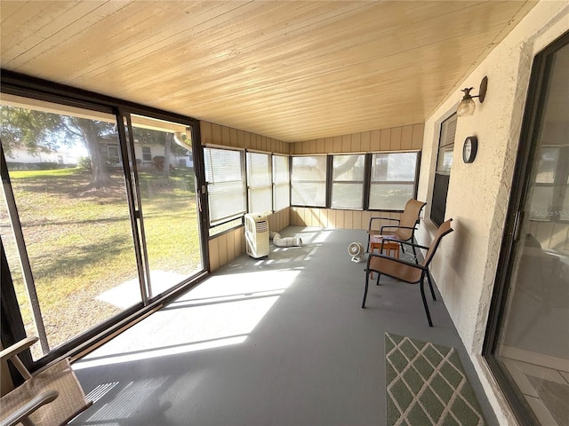 unfurnished sunroom featuring lofted ceiling, plenty of natural light, and wood ceiling