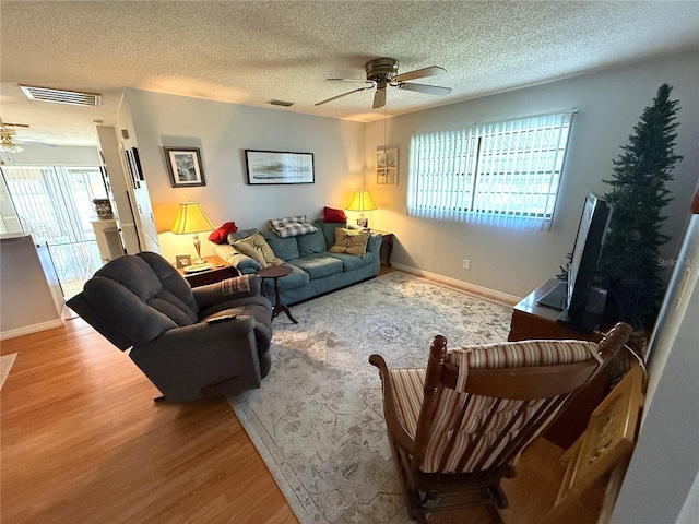 living room with ceiling fan, a textured ceiling, and hardwood / wood-style floors