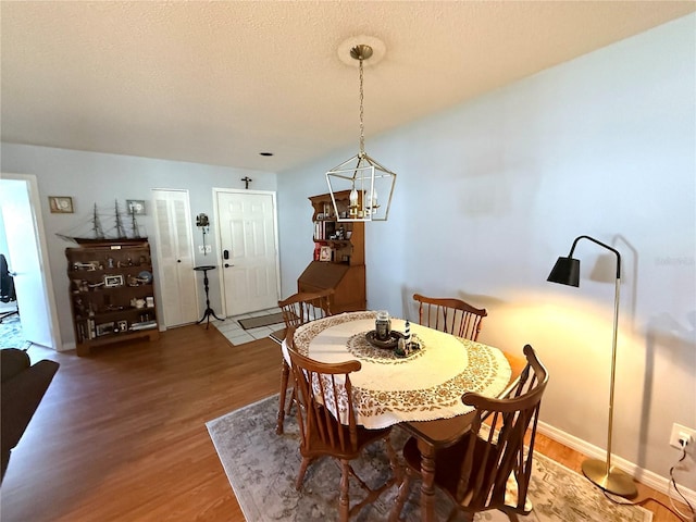 dining space featuring a textured ceiling, an inviting chandelier, and wood-type flooring