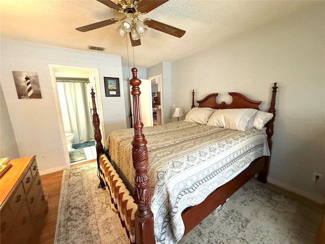 bedroom featuring ceiling fan, ensuite bath, wood-type flooring, and a textured ceiling