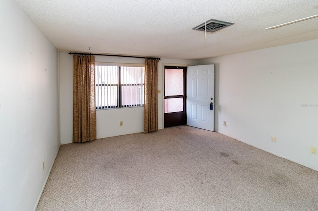 spare room with a textured ceiling and light colored carpet