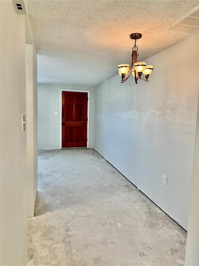 unfurnished dining area featuring a notable chandelier and a textured ceiling