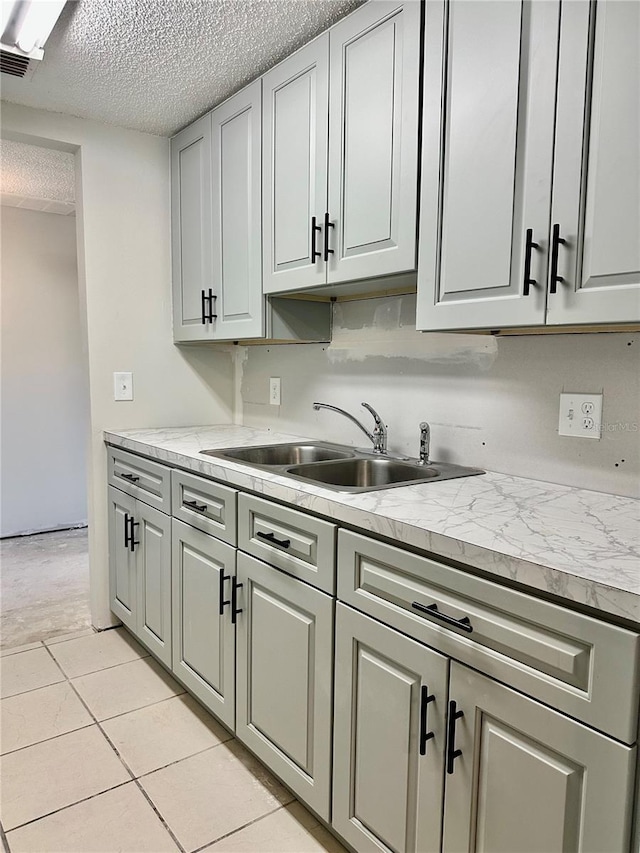 kitchen featuring sink, light tile patterned floors, and a textured ceiling