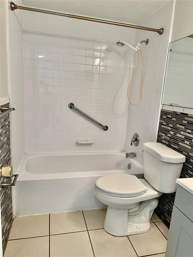 full bathroom featuring tile patterned flooring, vanity, tiled shower / bath combo, toilet, and a textured ceiling