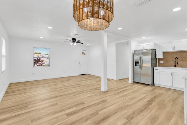 unfurnished living room with sink, ceiling fan, and light hardwood / wood-style flooring