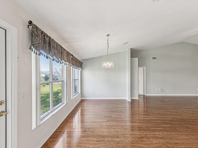 unfurnished room featuring dark wood-style flooring, a notable chandelier, vaulted ceiling, and baseboards