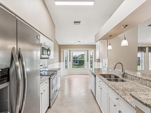 kitchen with visible vents, appliances with stainless steel finishes, white cabinetry, a sink, and light stone countertops