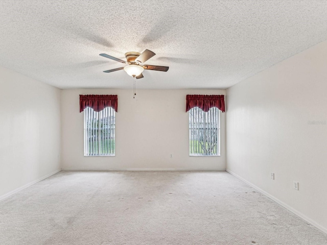 empty room featuring ceiling fan, baseboards, a textured ceiling, and light colored carpet