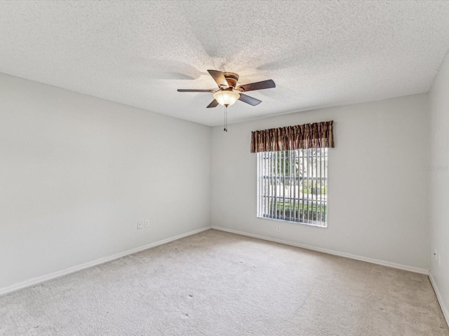 carpeted spare room featuring a textured ceiling, baseboards, and a ceiling fan