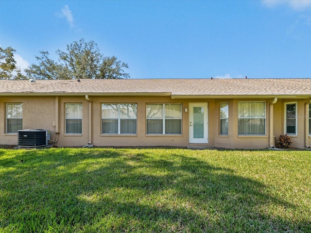 back of house featuring a yard, cooling unit, and stucco siding