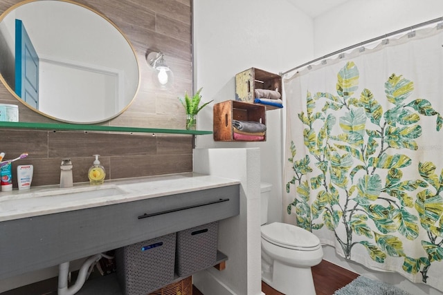 full bath with tasteful backsplash, toilet, and a sink