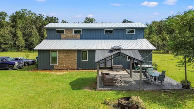 back of house with board and batten siding, an outdoor fire pit, a wooden deck, a lawn, and metal roof