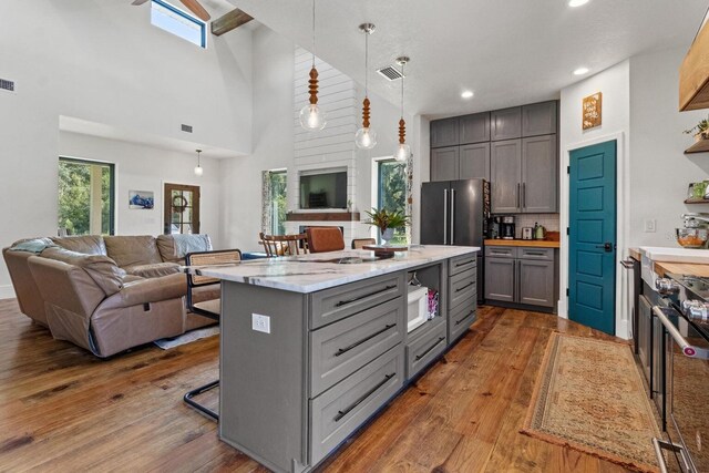 kitchen featuring gray cabinetry, open floor plan, dark wood-style floors, white microwave, and stove