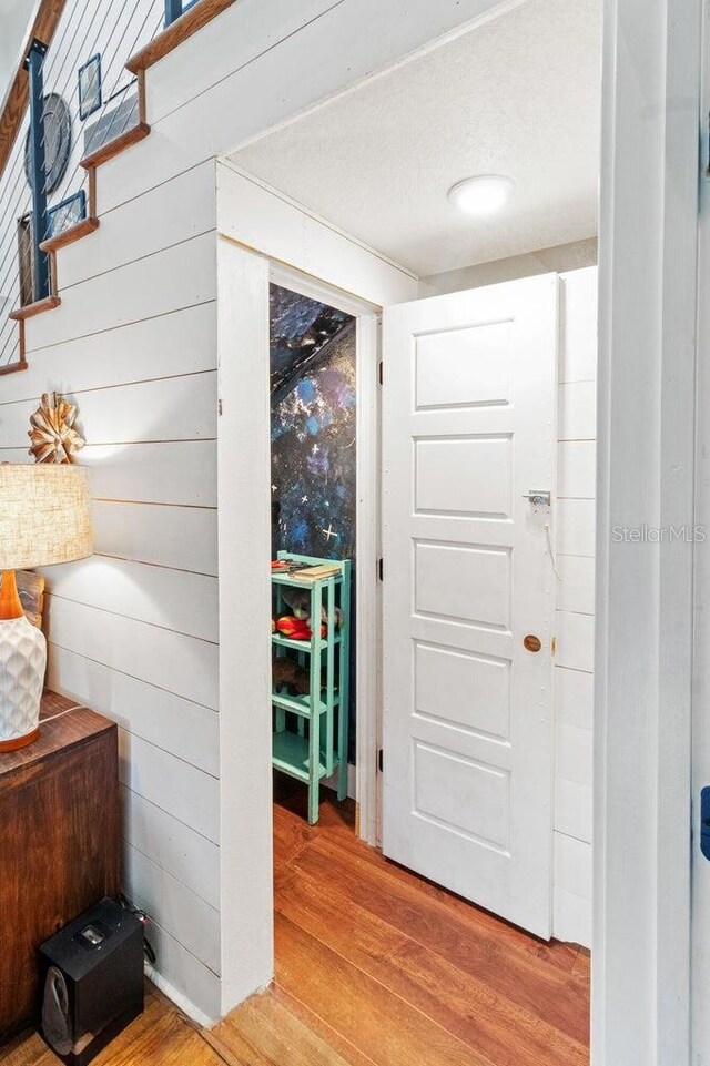 entrance foyer with stairway, wood walls, and wood finished floors