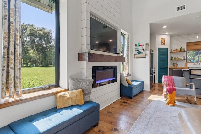 living area with visible vents, plenty of natural light, wood finished floors, and a fireplace