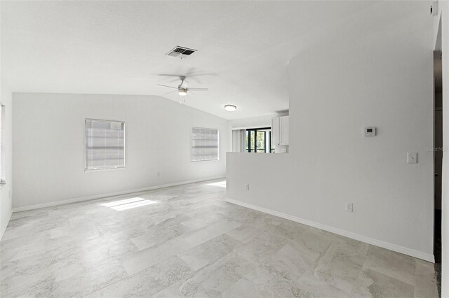 empty room featuring baseboards, lofted ceiling, ceiling fan, and visible vents