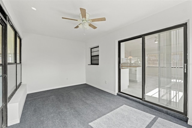 carpeted spare room featuring a wealth of natural light, baseboards, and ceiling fan