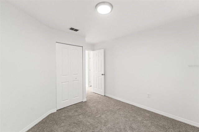 carpeted empty room featuring baseboards and visible vents