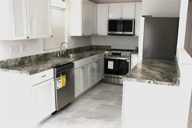 kitchen featuring a sink, dark countertops, white cabinets, and appliances with stainless steel finishes