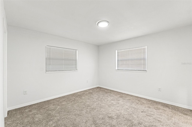 carpeted spare room featuring baseboards